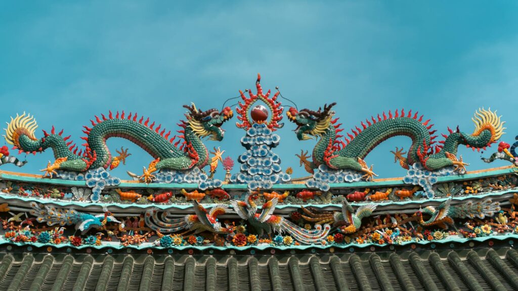 Intricate dragon sculptures on a temple roof under a clear sky.