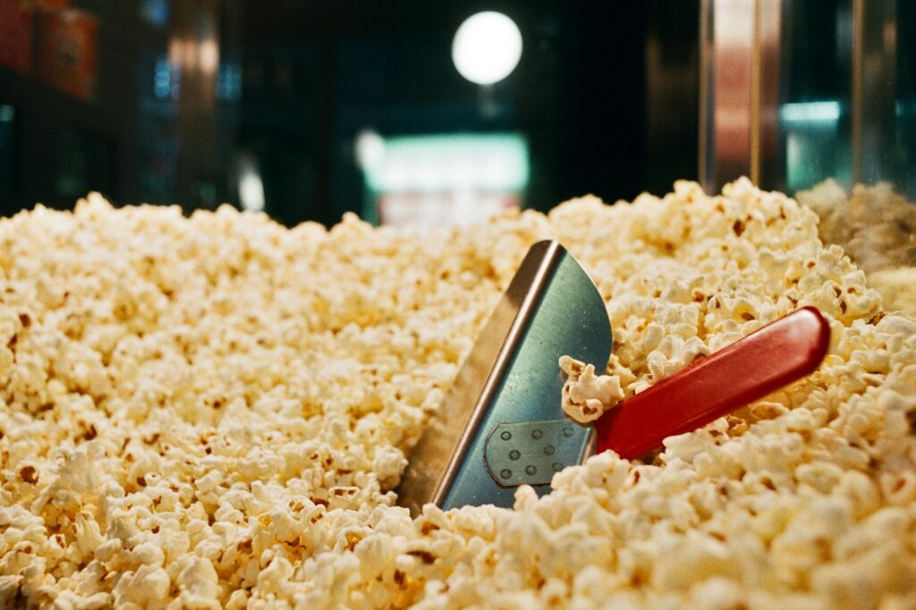 A detailed view of popcorn with a scoop, perfect for food advertising or cinema themes.